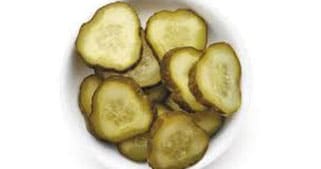 A white bowl filled with sliced pickles, shown from above.
